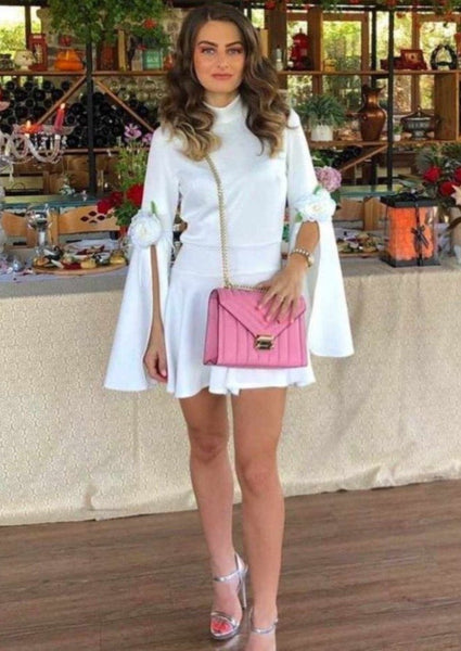 White Cassie Skater Dress with turtleneck, flutter sleeves, and flower detail above the knee.