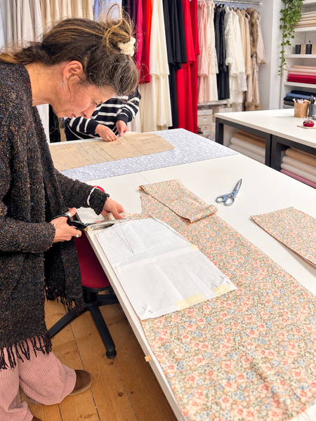 Adult sewing student cutting floral fabric around a paper pattern at Silvana Sewing Studio